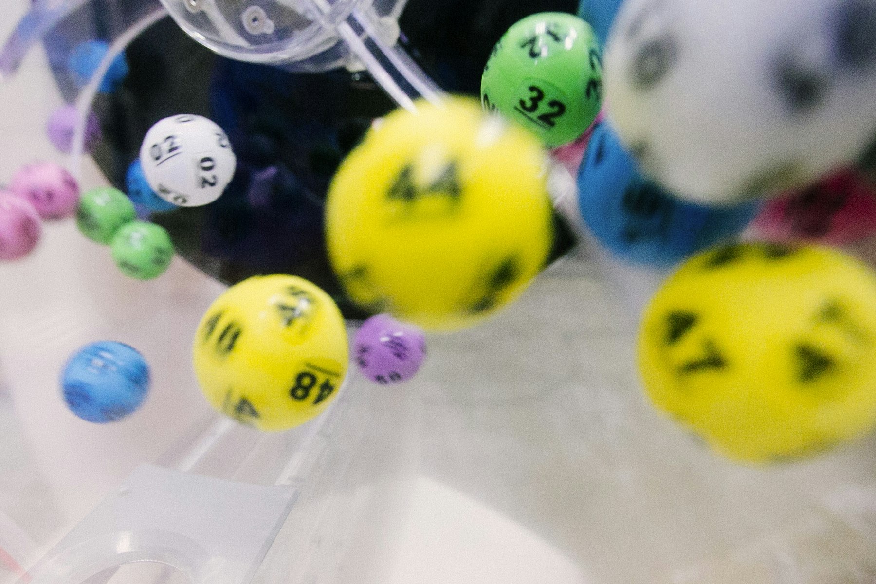 Numbered lottery balls tumbling in a clear mixing drum