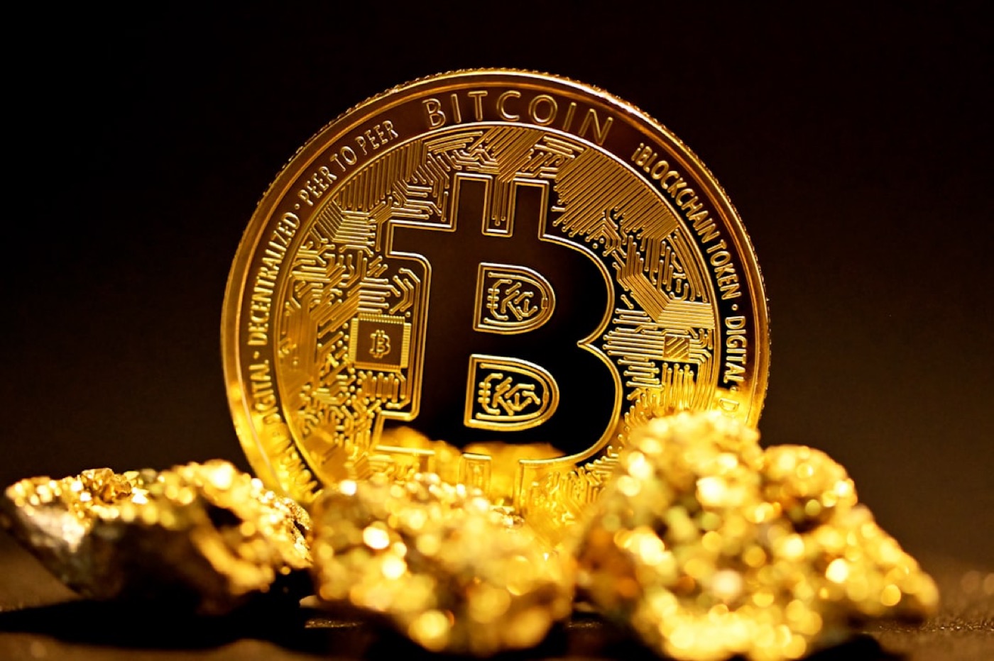 A bitcoin resting on a pile of gold nuggets
